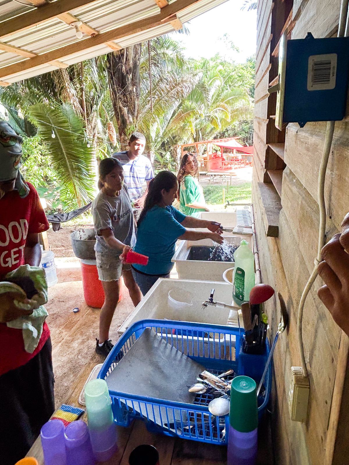 Camp Crew youths washing dishes and cups at the outdoor sinks