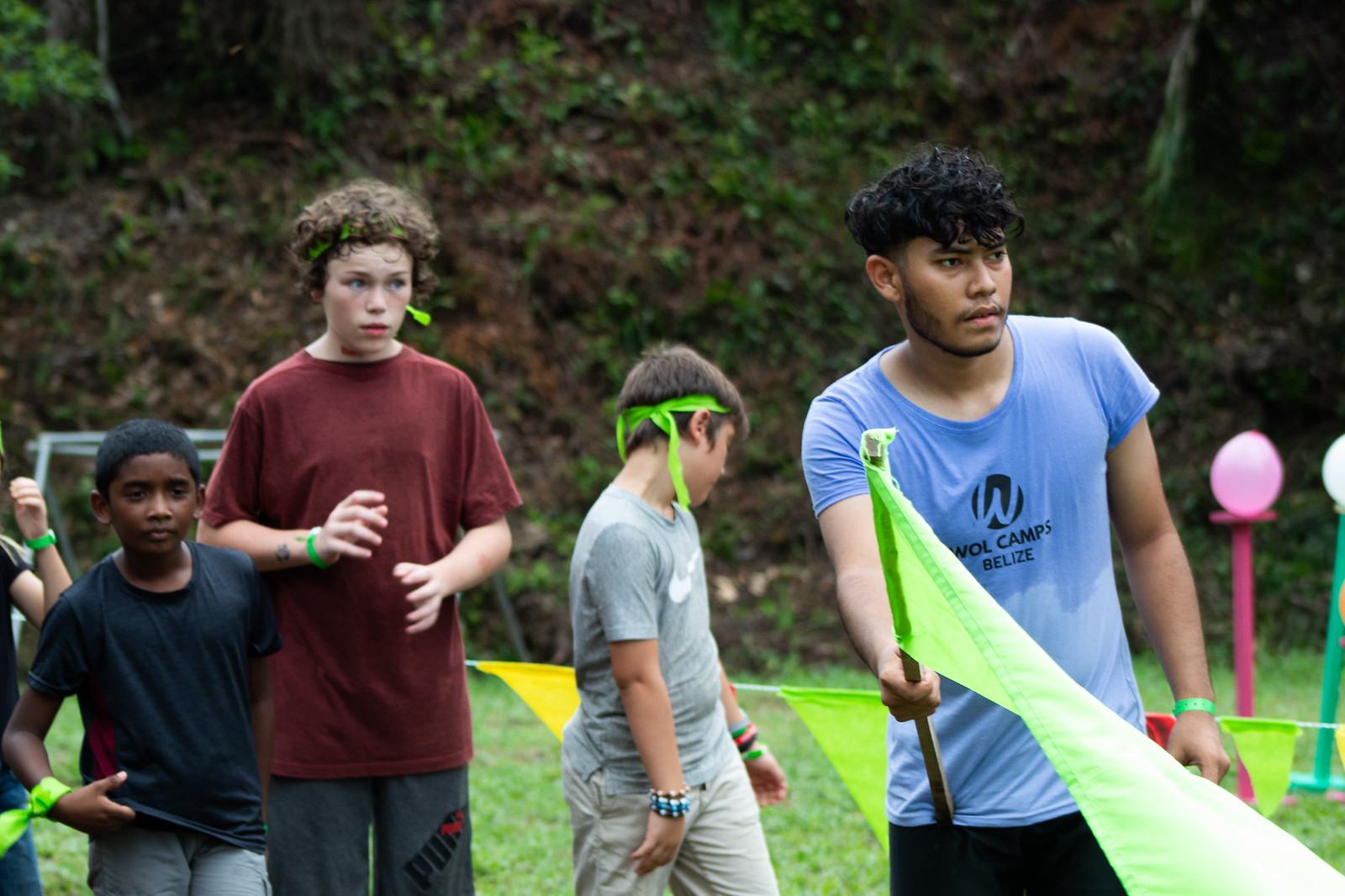Young leader with a flag running a game for junior campers