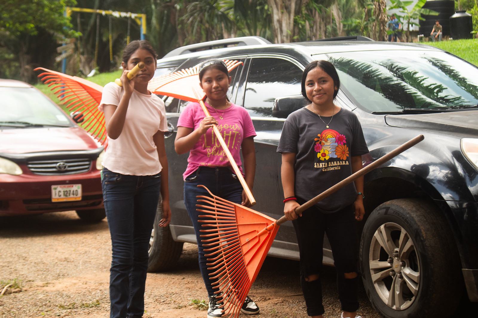 Three Camp Crew girls holding rakes, ready to tidy the grounds