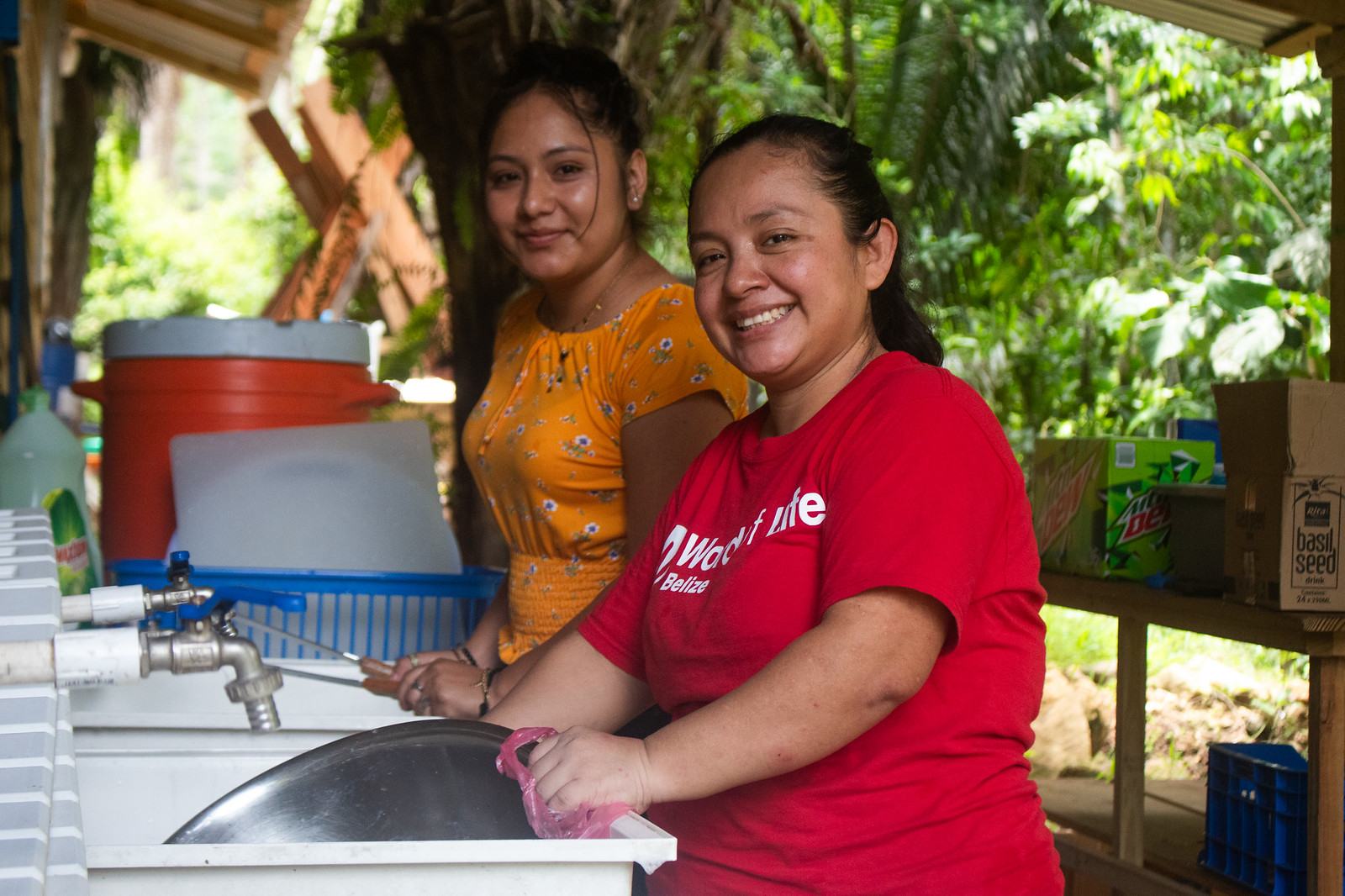 Two smiling Camp Crew members washing up at the sink