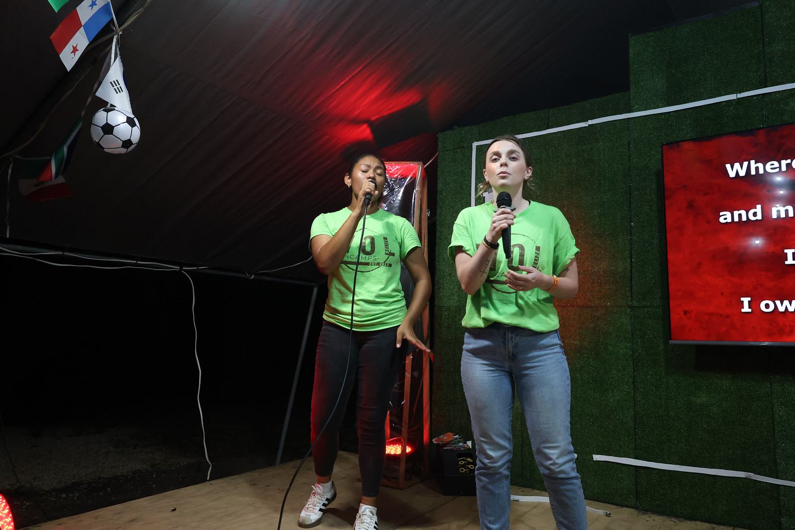 Two young women leading a song on stage at camp