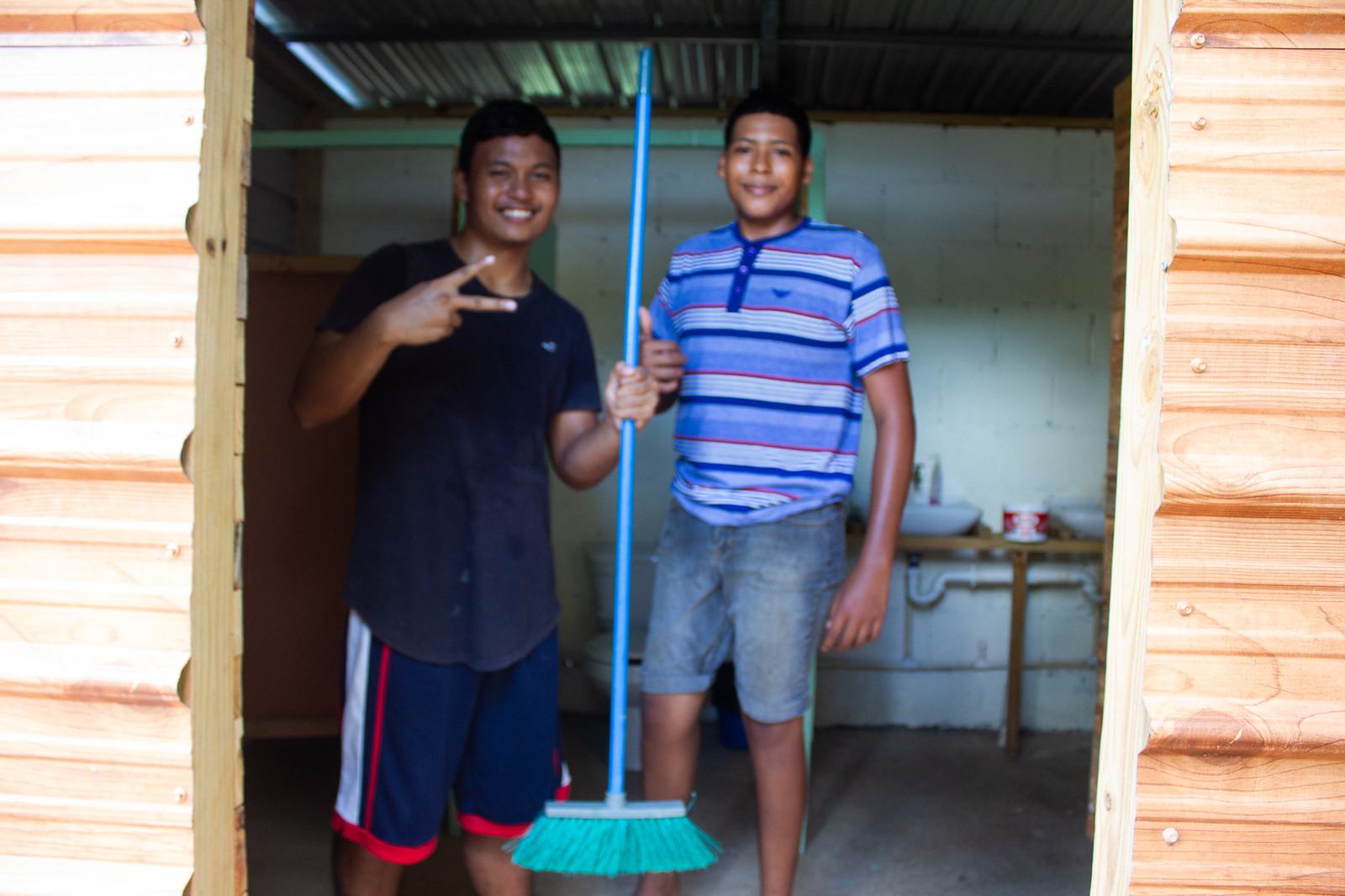 Two Camp Crew youths with a broom in a doorway