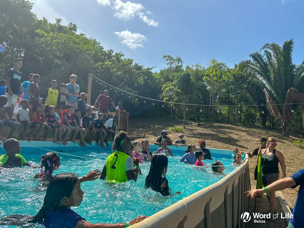 Campers in the pool with the jungle behind