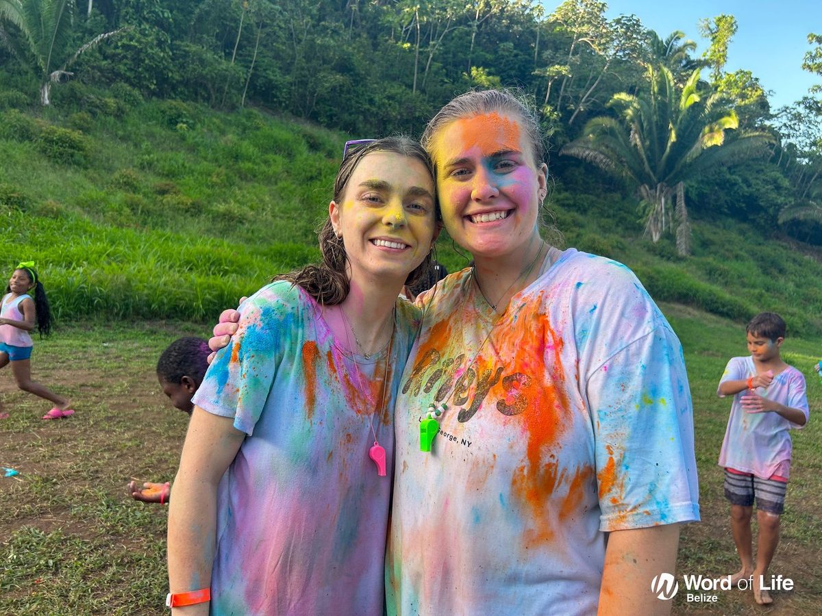 Two campers covered in bright colour powder after a Color Fest