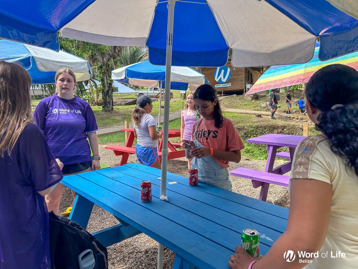 Picnic tables under colourful umbrellas on the camp grounds