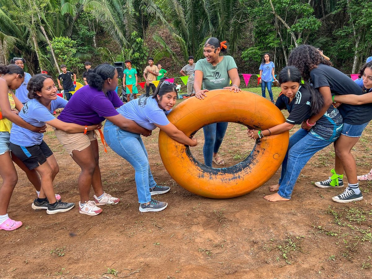 Teens working together to roll a giant tube in a team-building game