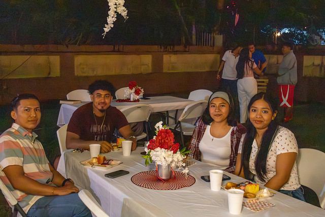 Young adults at dinner tables under string lights